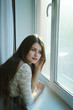 © natavilman - beautiful girl with long brown hair looking in the window