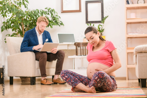 Picture Of Pregnant Woman Sitting On Floor And Touching Her Belly