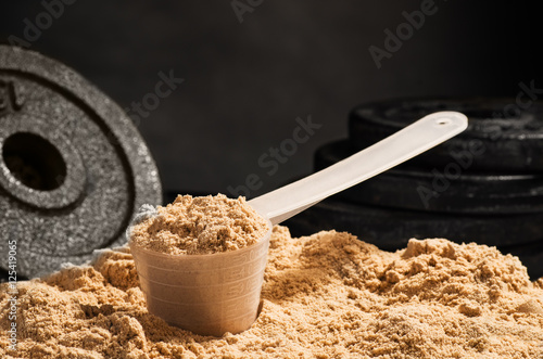 Fotografia Miarka serwatki proteina na czarnym tle. Wada czekoladowa