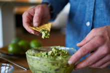 Dipping Tortilla Chip Into Freshly Made Guacamole To Check For Taste
