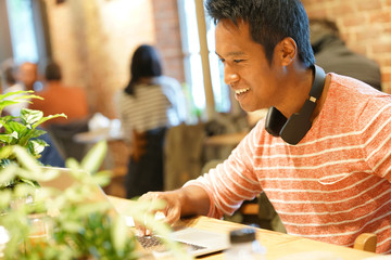 Young man sitting in restaurant websurfing on tablet