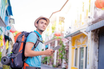 Wall Mural - Tourism and technology. Concept of online map. Traveling backpacker young man using digital tablet  outdoor.