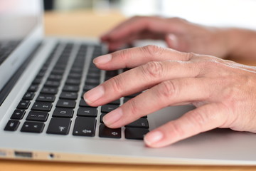 Hands typing on a laptop