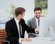 © ASDF - Smiling business men showing something on computer as colleague