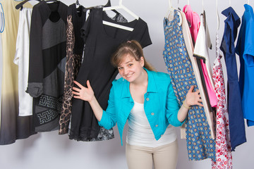 Happy young girl looked up from the clothes hanging on hangers