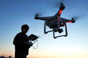 Wall Mural - young man operating of flying drone at sunset