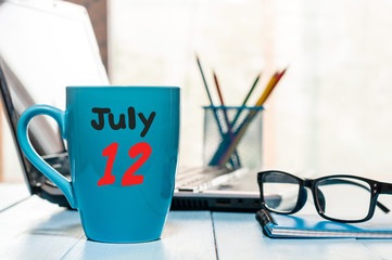 July 12th. Day 12 of month, color calendar on morning coffee cup at business workplace background. Summer concept. Empty space for text