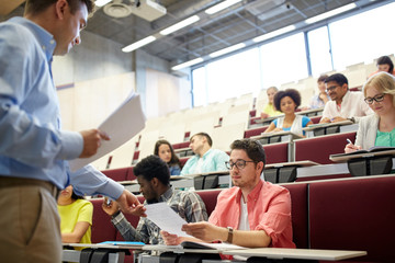 teacher giving tests to students at lecture