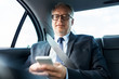 © Syda Productions - senior businessman texting on smartphone in car