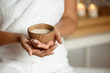 © Cookie Studio - Close up of girl holding coconut in spa salon.