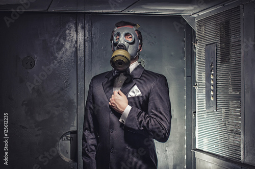 Zdjęcie XXL Mężczyzna w masce gazowej i kolorze, stojąc w starej windzie. Tajny agent, terrorysta czy biznesmen apokalipsy?