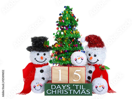 Fotografie, Obraz 15 Days until Christmas light beech wood blocks with red trim on a green base with tinsel christmas tree, mr and mrs snowman and snowball snowmen heads isolated on a white background