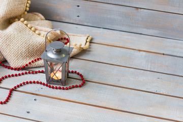 Christmas Lanterns, plaid and red beads on light wooden backgrou