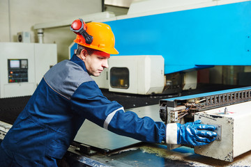 industrial factory worker operates punching machine