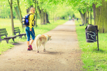 Wall Mural - Woman runner walking with dog in summer park