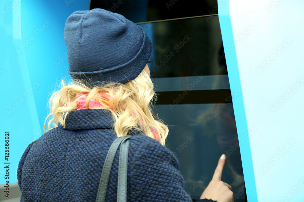 Young woman using public device with city map,routes and locations