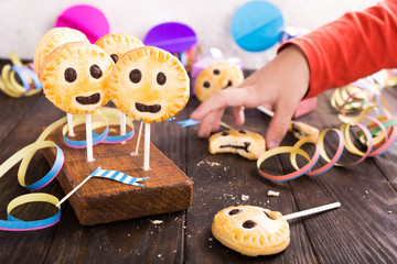 Wall Mural - Homemade shortbread smiley cookies with dark chocolate on stick called pie pops. Children's party background.