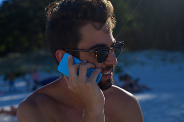 young man talking on telephone in the beach