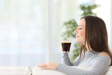 Wall Mural - Woman smelling a cup of coffee at home