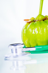 Wall Mural - Closeup garcinia cambogia and stethoscope on white background.