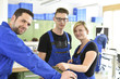 © Westend61 - Portrait of smiling instructor with trainees in workshop