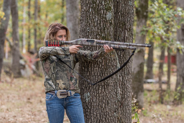 Woman hunting and aiming a shotgun