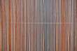 Wood cladding wall which various tone texture of wooden stripes use as partition or seamless fence in vertical line which use as building facade decoration and modern household or contemporary office.