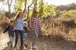 © Monkey Business - Young white family walking on a path in sunlight, front view