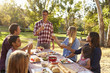 © Monkey Business - Two families making a toast at picnic at a table in a park