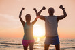 Couple with their hands up high standing in the sunset