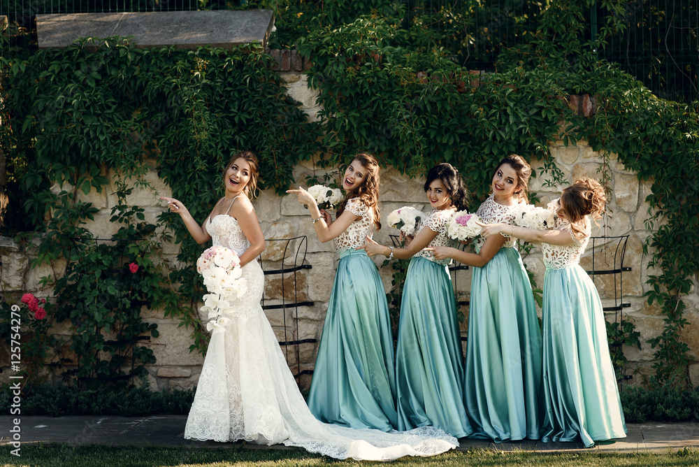 Funny bridesmaids walk behind funny bride along the wall outside Stock  Photo | Adobe Stock