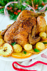 Christmas baked chicken (turkey) with oranges and apples on a wh