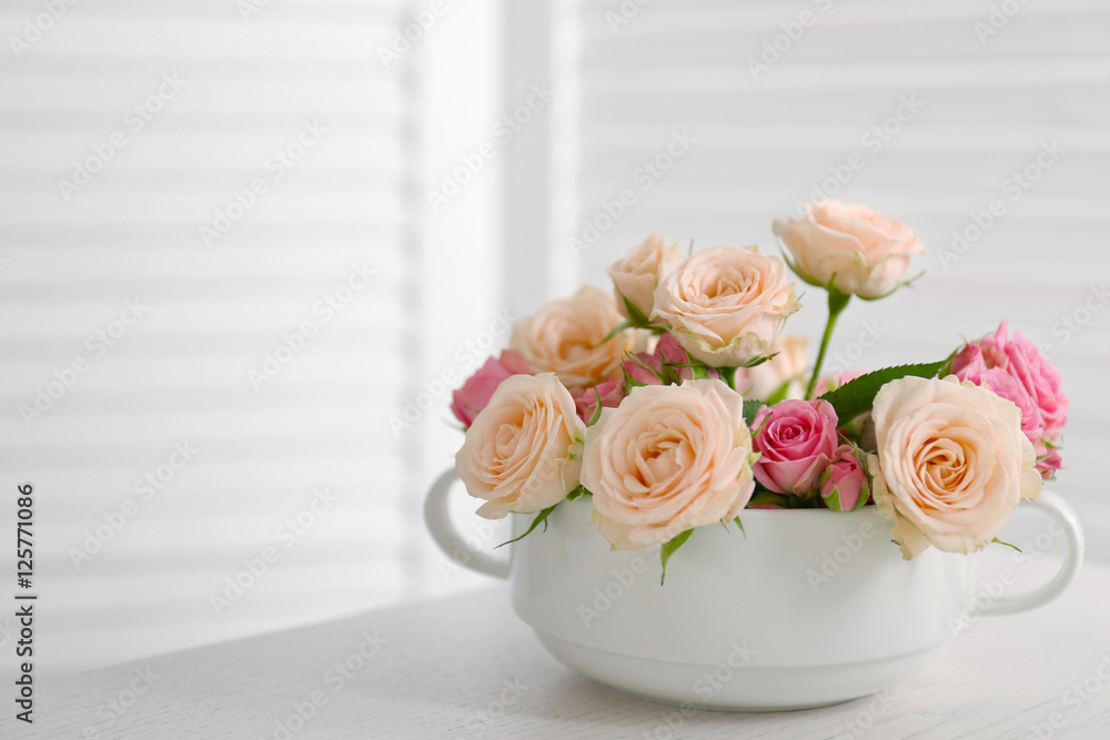 Bouquet of beautiful roses in a cup on a  table