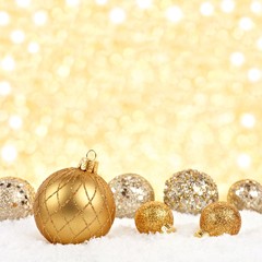 Wall Mural - Golden Christmas ornaments in snow with twinkling gold background