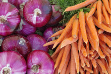 Background Of Red Onions And Carrots At A Farmer's Market.