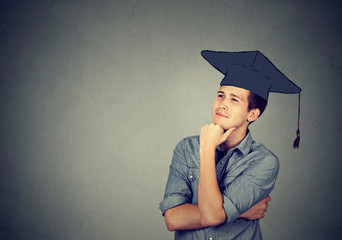 graduate student man in cap gown looking up thinking