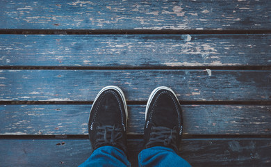 Wall Mural - Looking down on feet and a wooden surface, space for text. selective focus