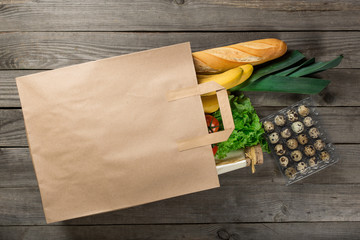 Canvas Print - Different food in paper bag on wooden background