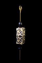 canape with cheese, sesame and olives on black background with r