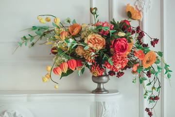 autumn bouquet on the fireplace. The cozy interior in white tones