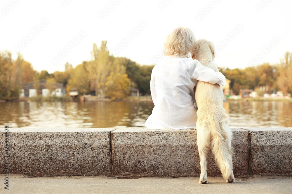 Senior woman with big dog sitting back on bund