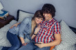 © David Pereiras - Happy couple in love looking electronic tablet on bed