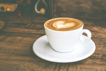 Close up white coffee cup with heart shape latte art on wood tab