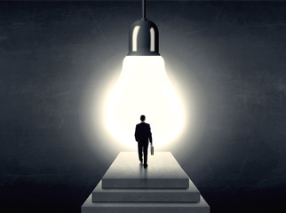 Wall Mural - Man standing on a step in front of a huge light bulb