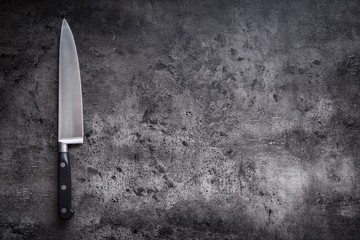Kitchen knife on concrete or wooden board.
