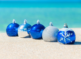 christmas tree blue and silver balls decorations on sandy beach