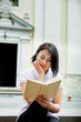 © bondarillia - Woman is reading book. Girl with  in white polo, black pant and red shoes  sitting on stairs near university at campus  learning, studying. teenager  outdoors  open