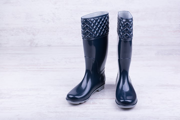 Pair of blue rubber boots on white wooden background