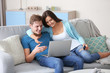 © Africa Studio - Happy couple with credit card sitting on sofa and making online shopping
