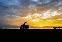 A Silhouette Girl Rider And Her Camera On Big Bike In Sunset .